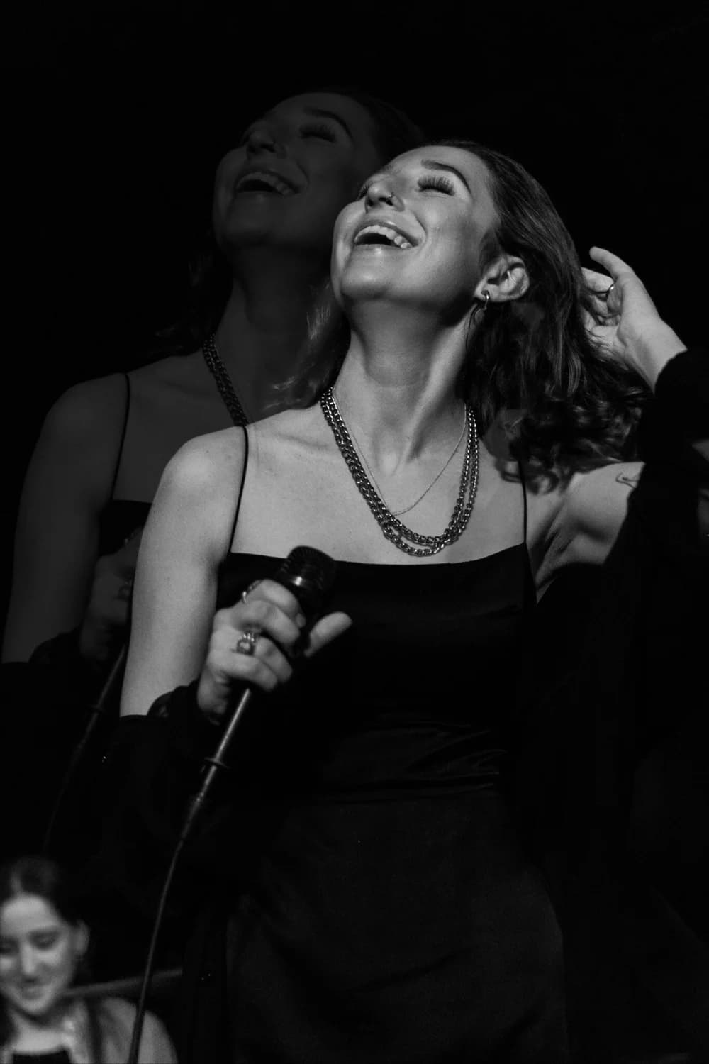 Black-and-white concert photo shot by Liz of a singer laughing on stage
